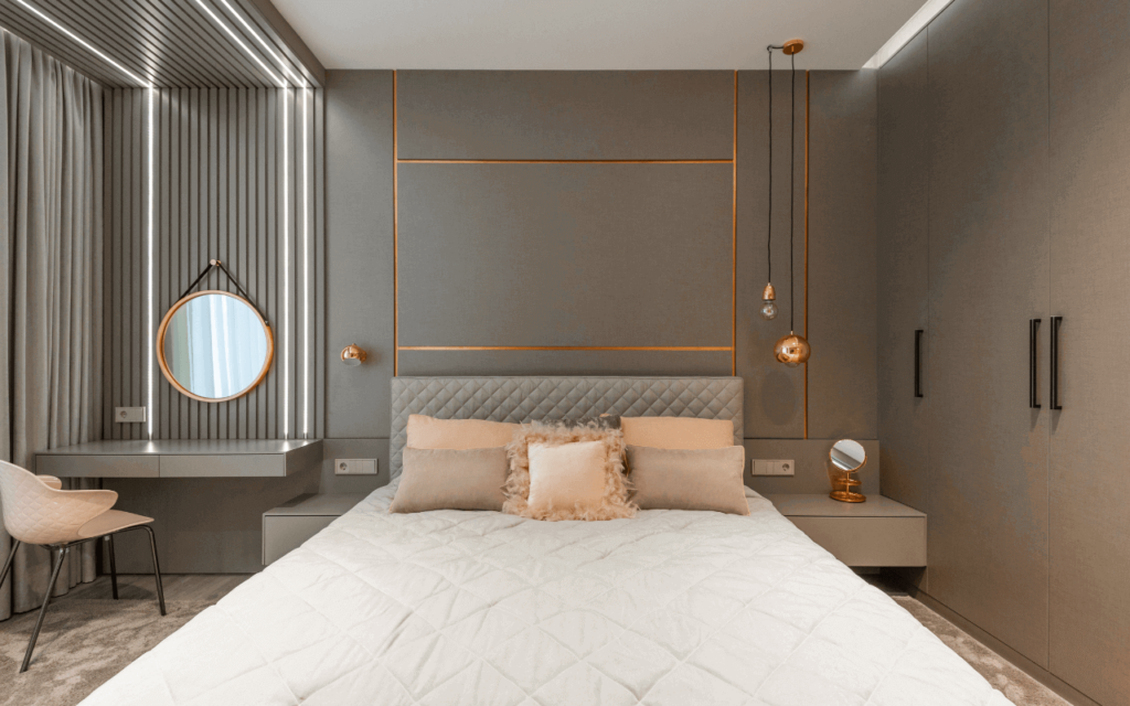 Ein Schlafzimmer mit pfirsichfarbenen Kissen auf hellbraunem Hintergrund und goldenen Metallakzenten