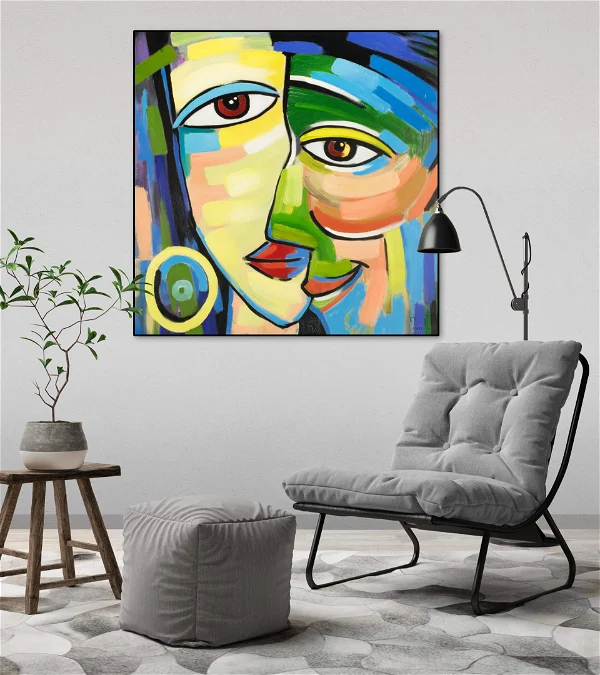 Buntes modernes kubistisches Gemälde mit abstrakten Gesichtern über einem grauen Sessel in einem stilvollen Wohnzimmer mit Zimmerpflanzen und minimalistischem Dekor