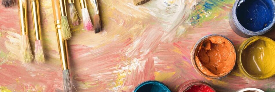 Pinsel und eine mit bunten Farben verschmierte Palette, mit offenen Gläsern herum.