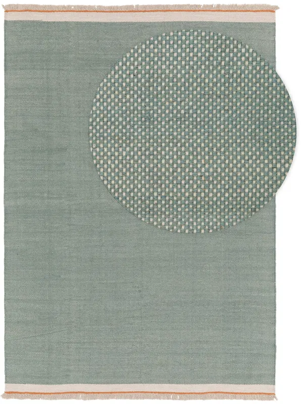 Weicher mintgrüner Teppich mit eingewebtem kreisförmigem Muster an einer Ecke, mit minimalistischem Design und Fransenkanten