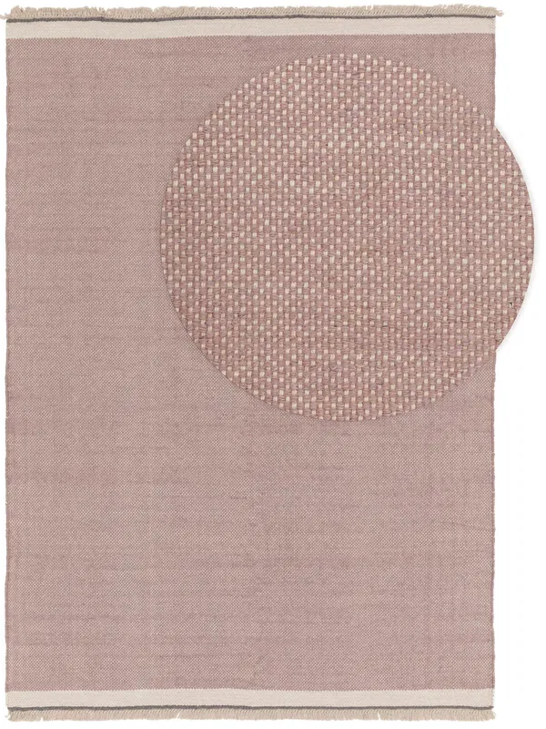 Weicher, rosafarbener Teppich mit einem gewebten, kreisförmigen Muster an einer Ecke, der ein minimalistisches Design mit Fransenkanten bietet.