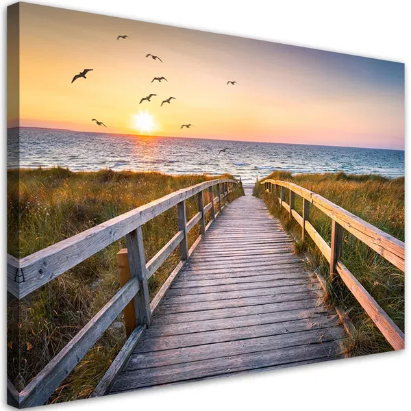 Holzpromenade, die bei Sonnenuntergang zum Strand führt, mit Möwen, die über das Meer fliegen, und hohem Gras entlang des Weges